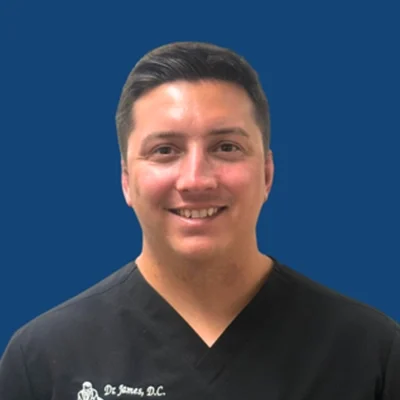 Chiropractor Nathan W. James Smiling In Front Of Blue Background